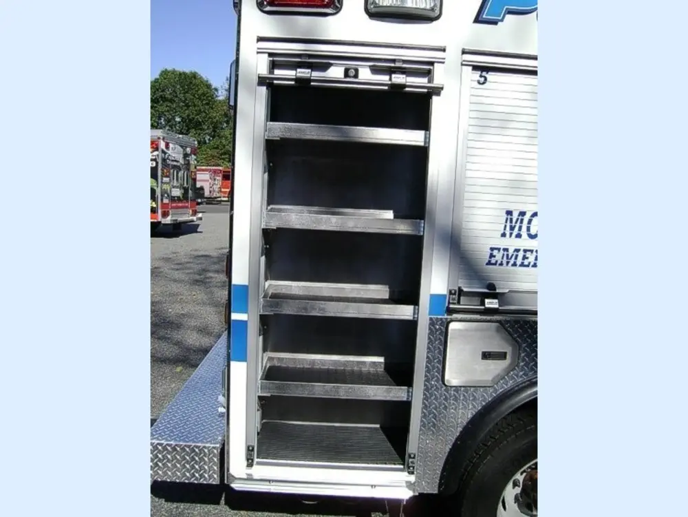 Exterior view of small fire truck showing cab, body compartments, and wheel/tire area.