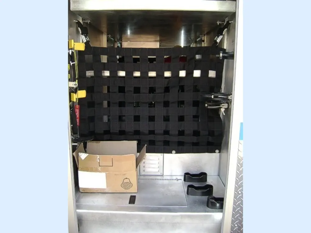 Exterior view of small fire truck showing cab, body compartments, and wheel/tire area.