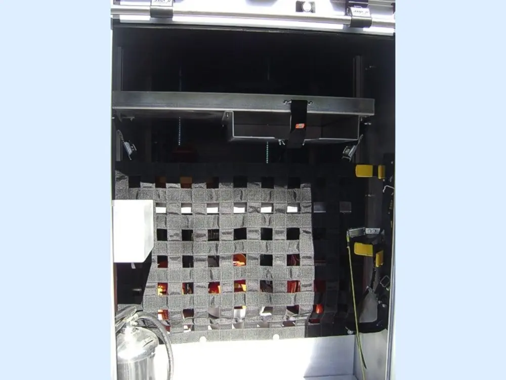 Exterior view of small fire truck showing cab, body compartments, and wheel/tire area.