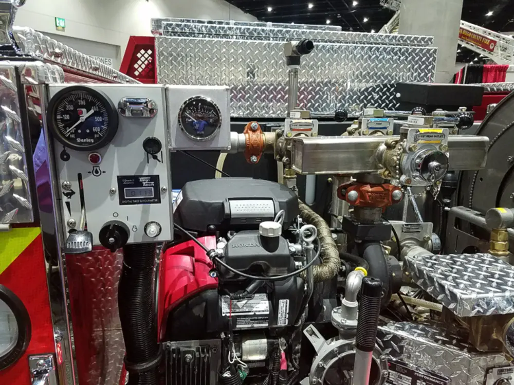 Exterior view of small fire truck showing cab, body compartments, and wheel/tire area.