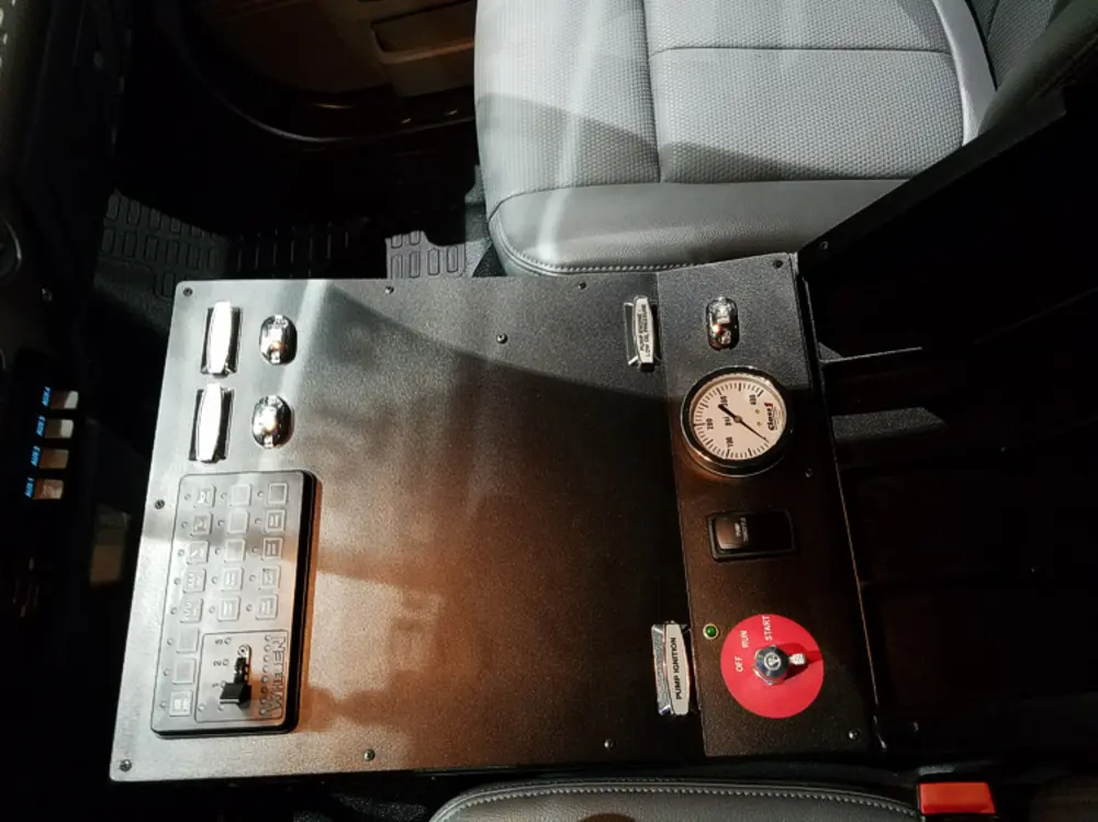 Exterior view of small fire truck showing cab, body compartments, and wheel/tire area.