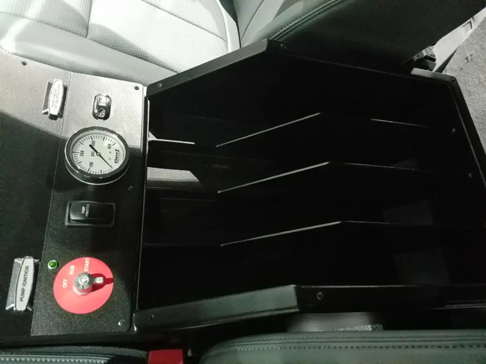 Exterior view of small fire truck showing cab, body compartments, and wheel/tire area.