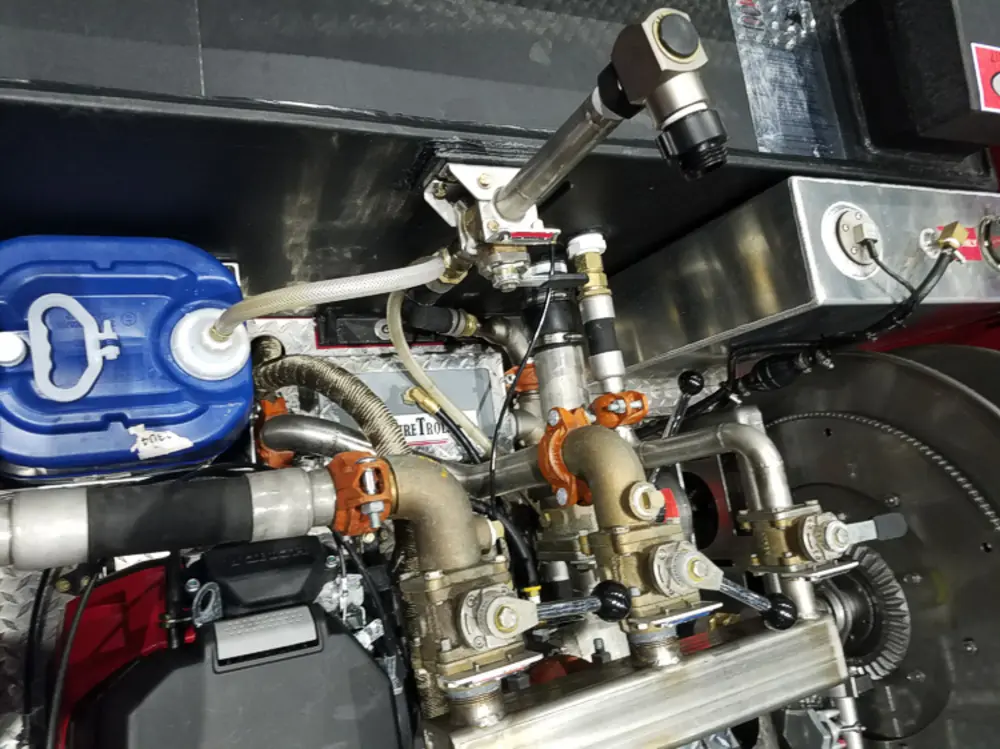 Exterior view of small fire truck showing cab, body compartments, and wheel/tire area.