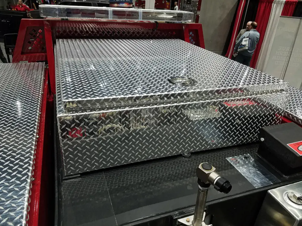 Exterior view of small fire truck showing cab, body compartments, and wheel/tire area.