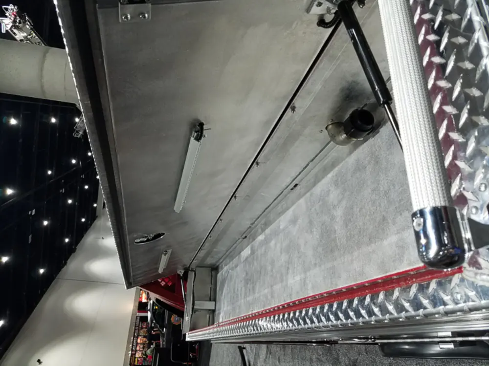 Exterior view of small fire truck showing cab, body compartments, and wheel/tire area.