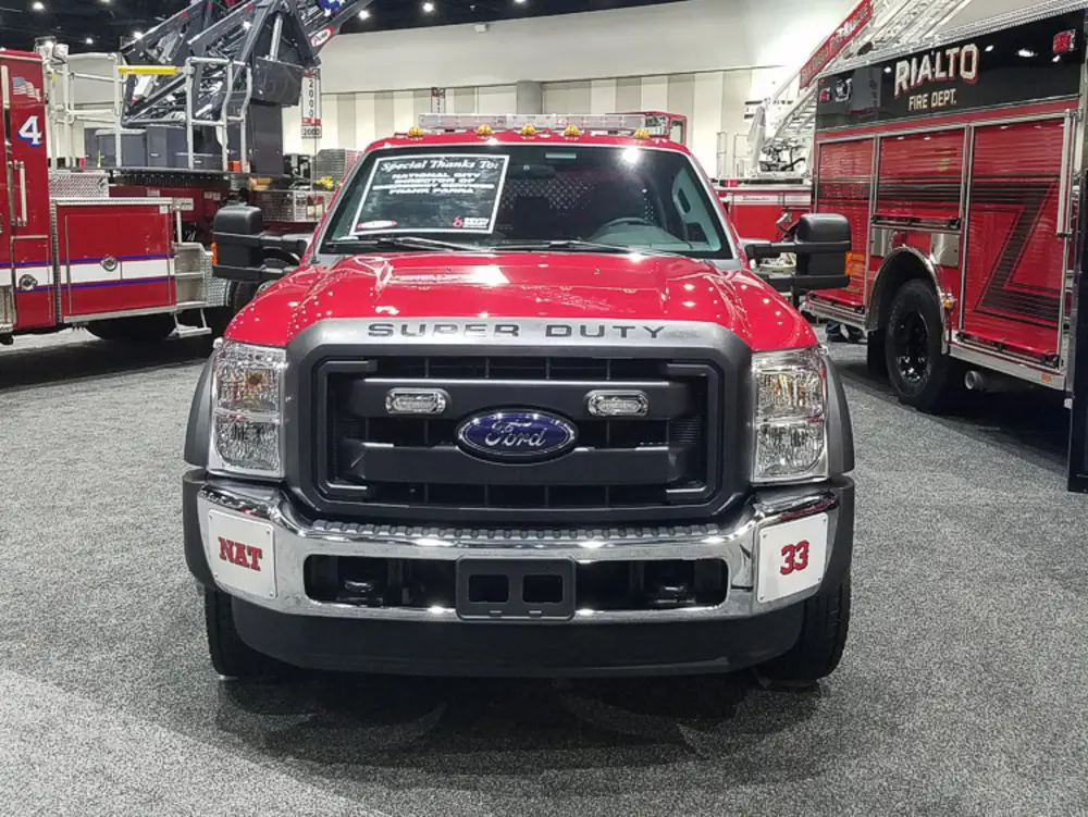 Exterior view of small fire truck showing cab, body compartments, and wheel/tire area.
