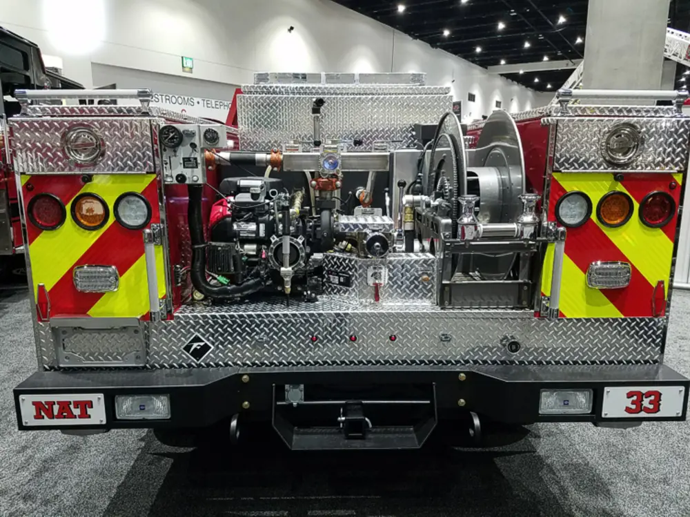 Exterior view of small fire truck showing cab, body compartments, and wheel/tire area.