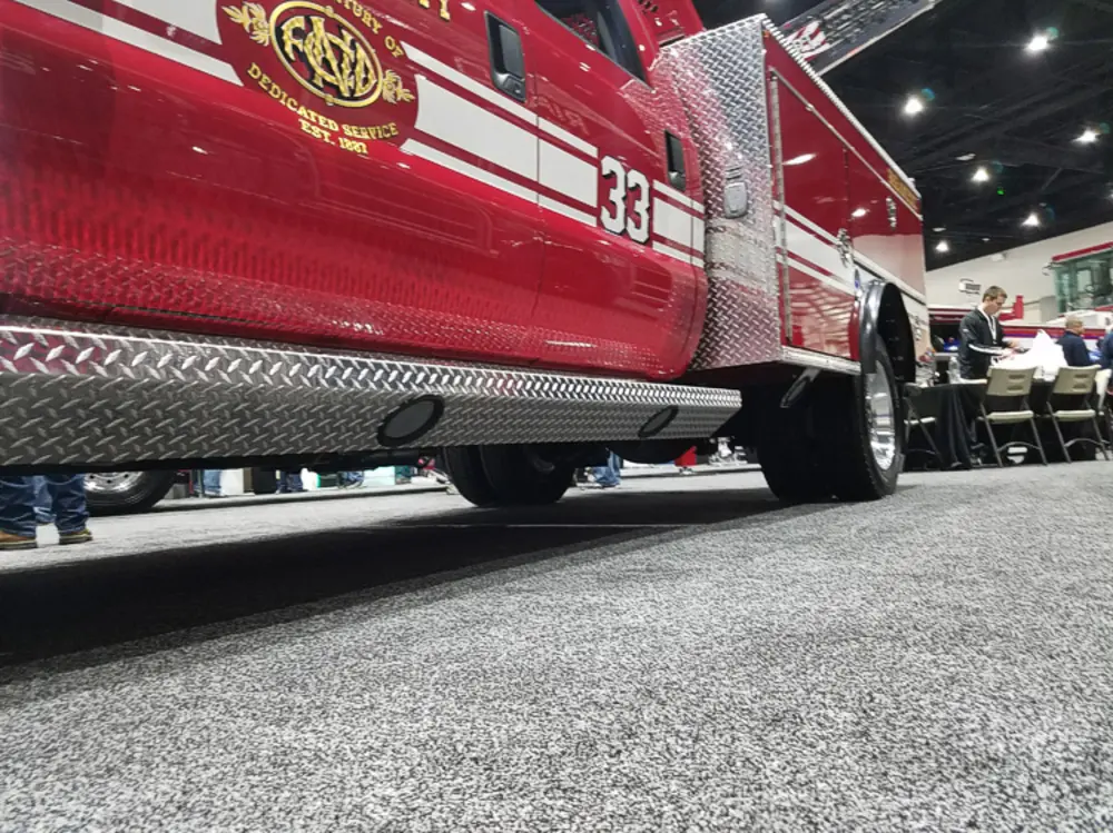 Exterior view of small fire truck showing cab, body compartments, and wheel/tire area.