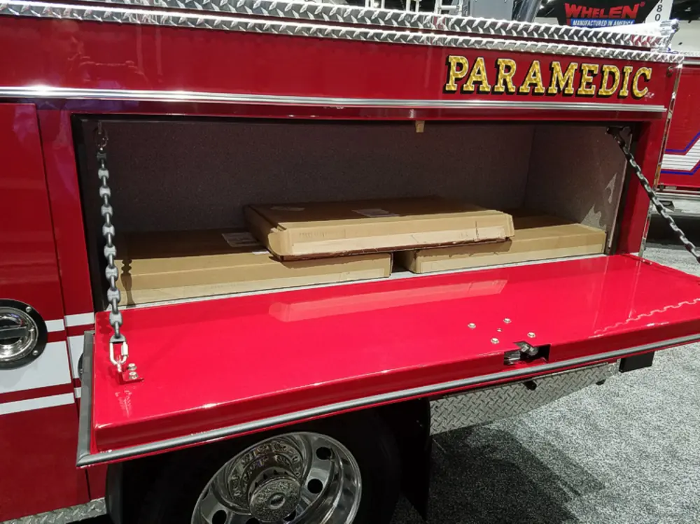 Exterior view of small fire truck showing cab, body compartments, and wheel/tire area.