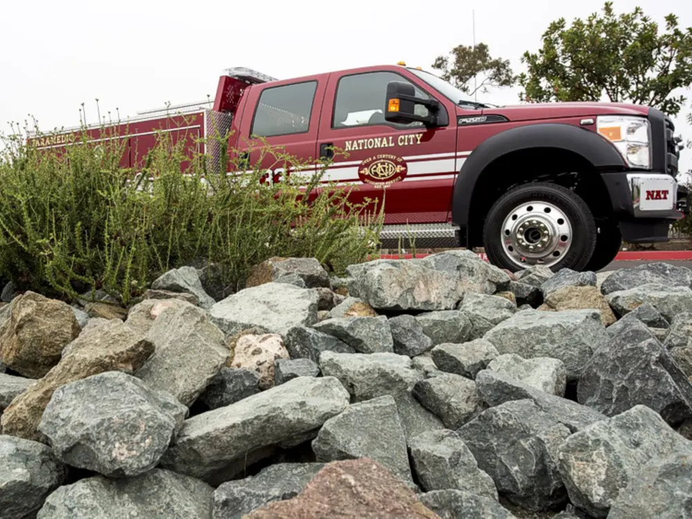 Exterior view of small fire truck showing cab, body compartments, and wheel/tire area.