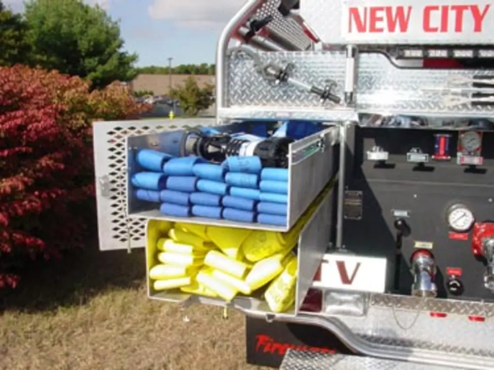 Exterior view of small fire truck showing cab, body compartments, and wheel/tire area.