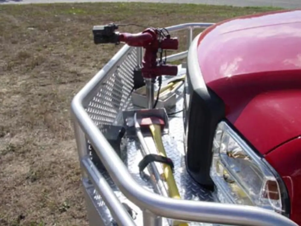 Exterior view of small fire truck showing cab, body compartments, and wheel/tire area.