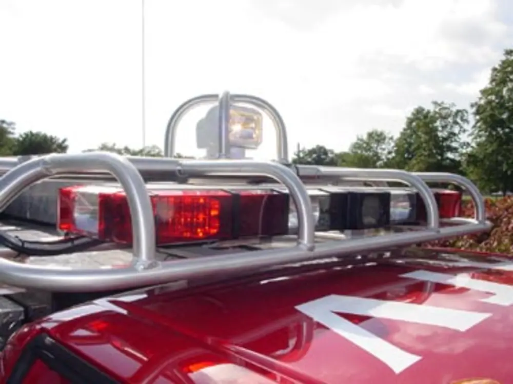 Exterior view of small fire truck showing cab, body compartments, and wheel/tire area.