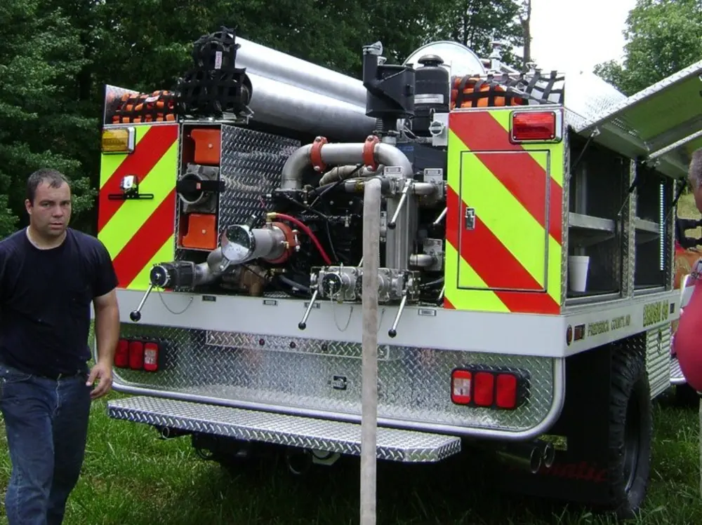 Exterior view of small fire truck showing cab, body compartments, and wheel/tire area.