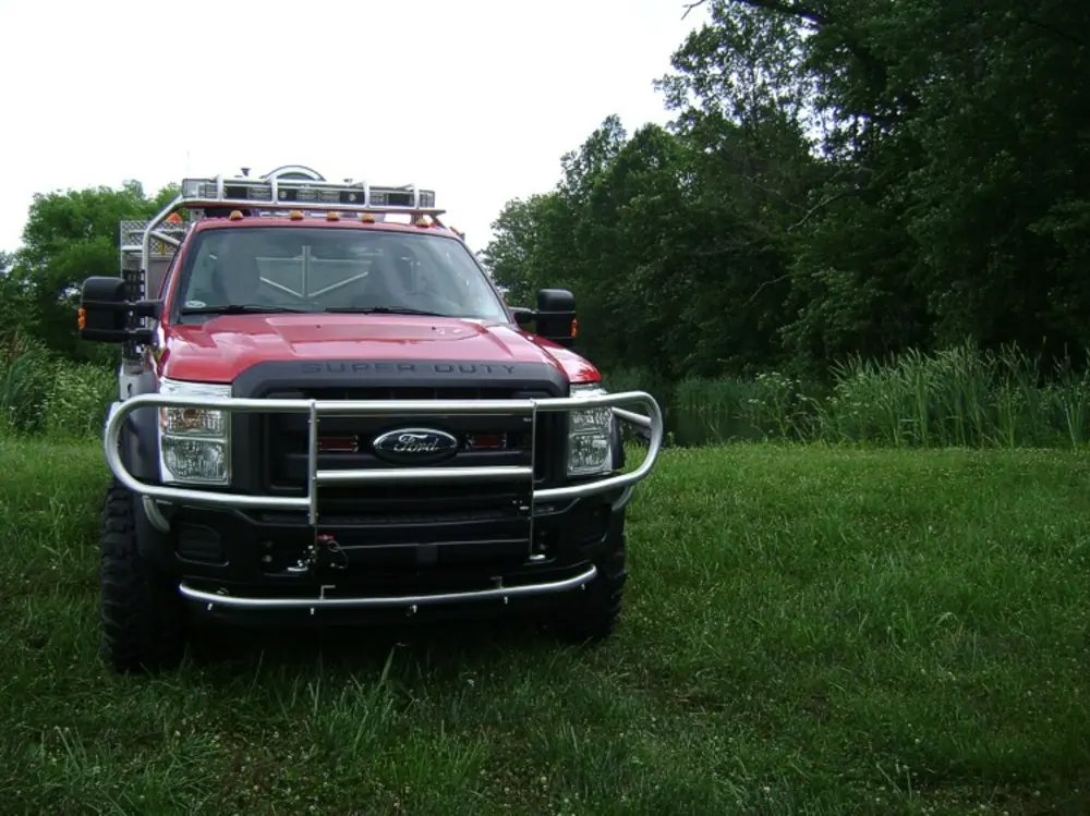 Exterior view of small fire truck showing cab, body compartments, and wheel/tire area.