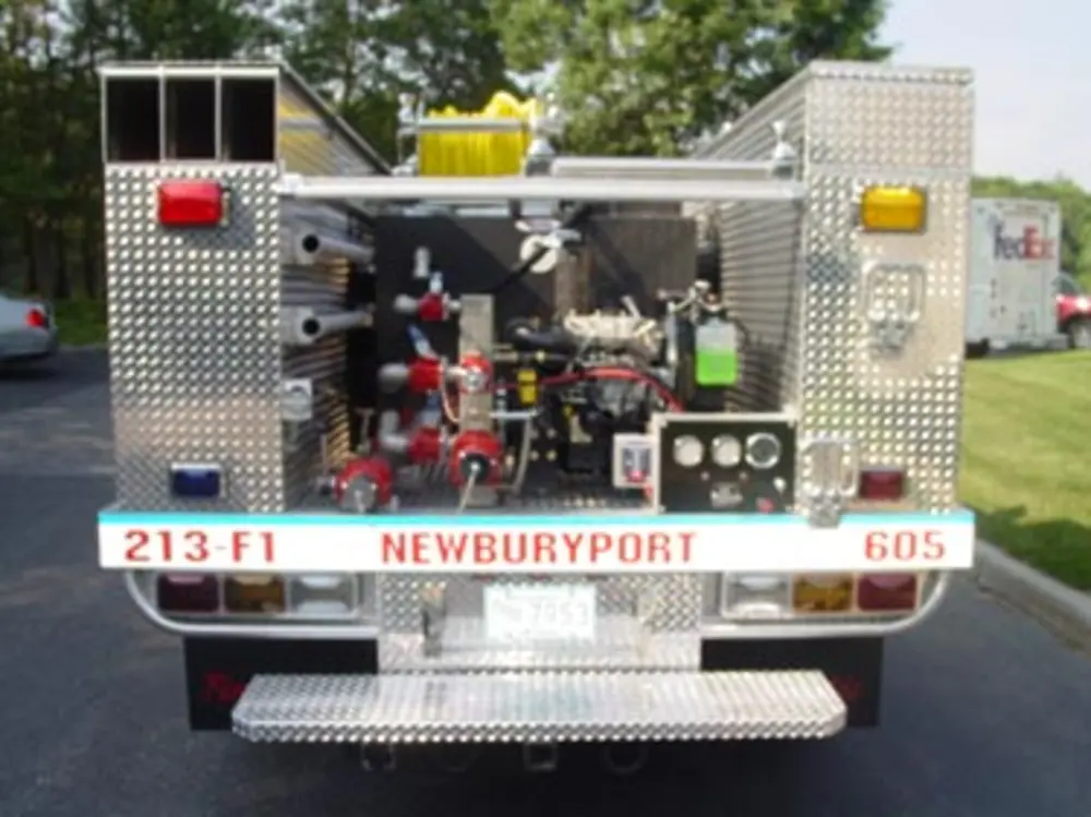 Exterior view of small fire truck showing cab, body compartments, and wheel/tire area.