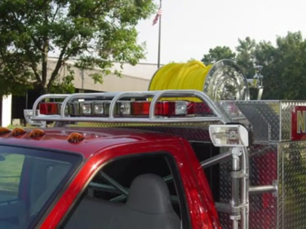 Exterior view of small fire truck showing cab, body compartments, and wheel/tire area.