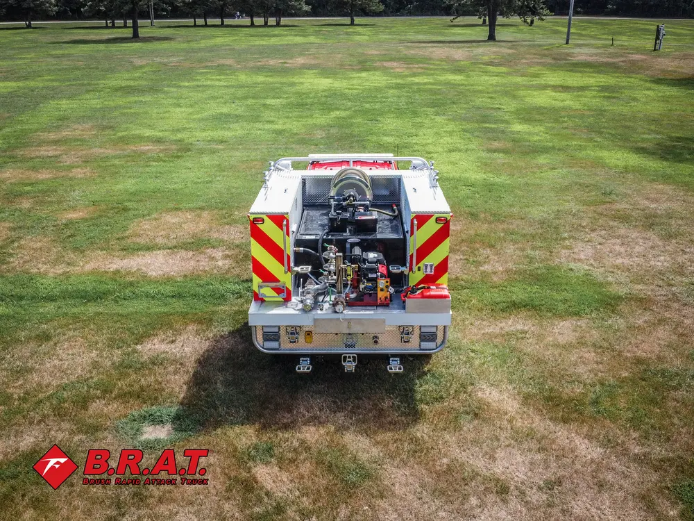 Exterior view of small fire truck showing cab, body compartments, and wheel/tire area.