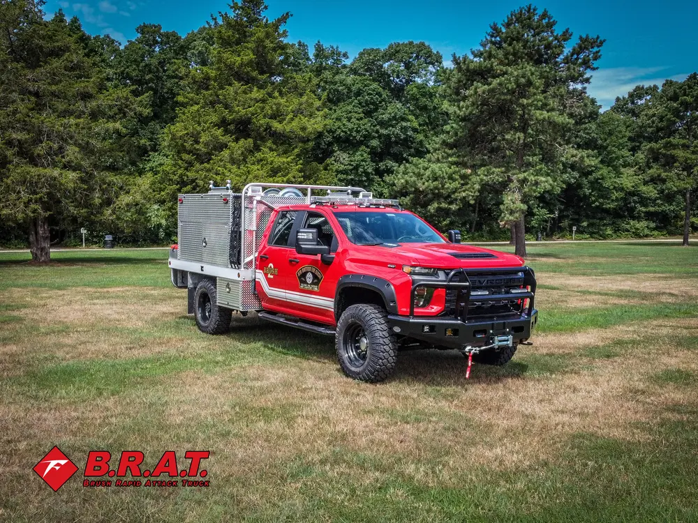 Exterior view of small fire truck showing cab, body compartments, and wheel/tire area.