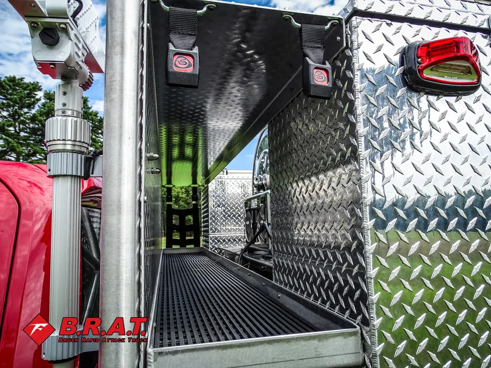 Exterior view of small fire truck showing cab, body compartments, and wheel/tire area.