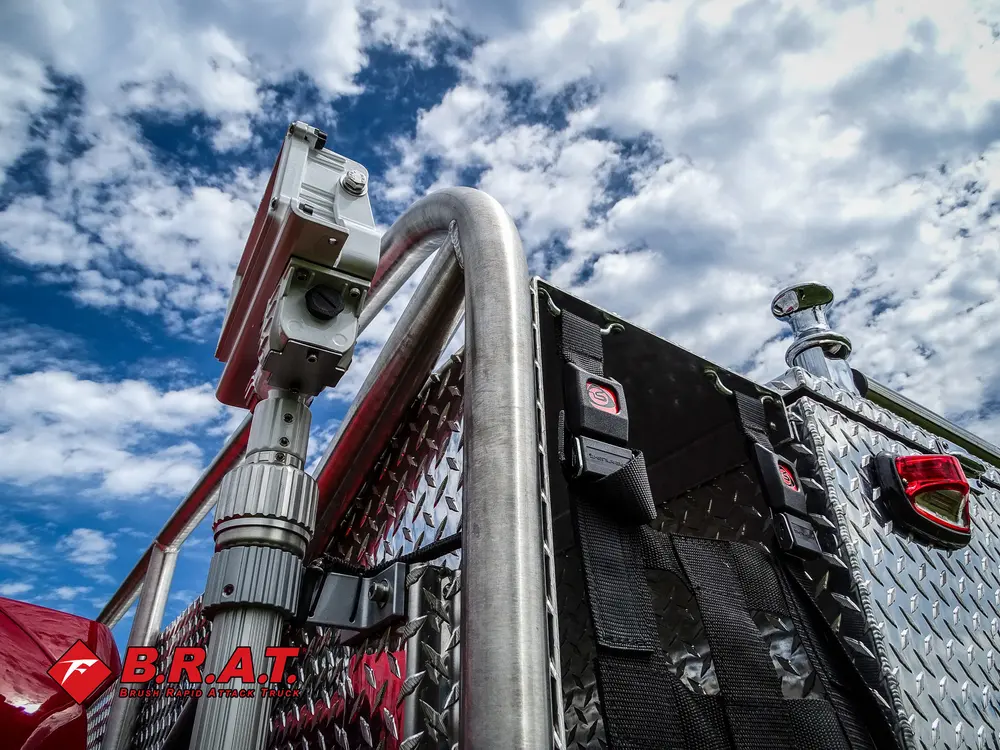 Exterior view of small fire truck showing cab, body compartments, and wheel/tire area.