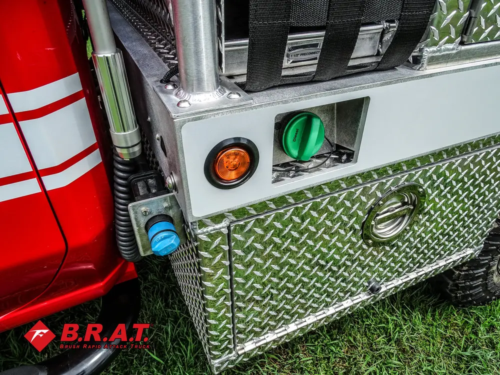 Exterior view of small fire truck showing cab, body compartments, and wheel/tire area.