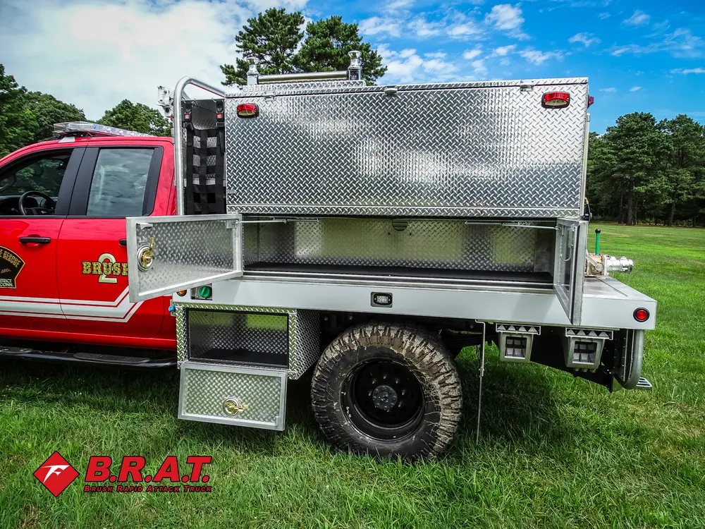 Exterior view of small fire truck showing cab, body compartments, and wheel/tire area.