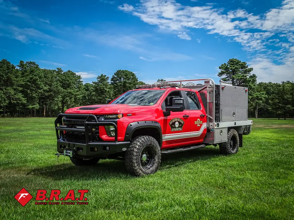 Exterior view of small fire truck showing cab, body compartments, and wheel/tire area.