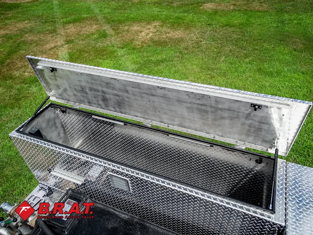 Exterior view of small fire truck showing cab, body compartments, and wheel/tire area.