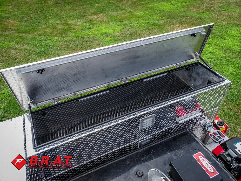 Exterior view of small fire truck showing cab, body compartments, and wheel/tire area.