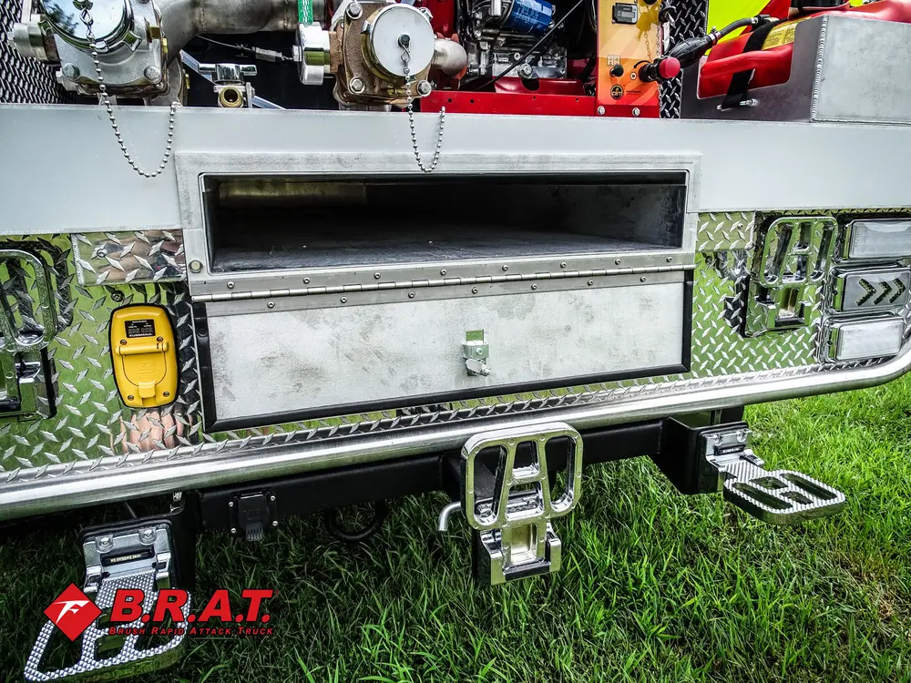 Exterior view of small fire truck showing cab, body compartments, and wheel/tire area.
