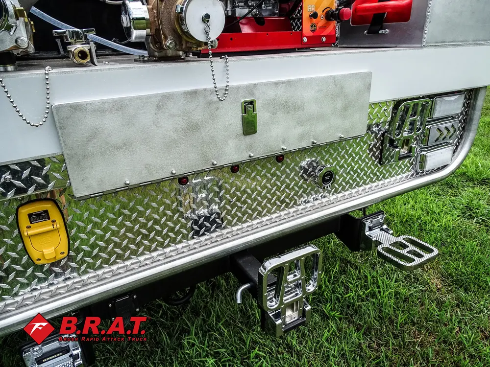 Exterior view of small fire truck showing cab, body compartments, and wheel/tire area.