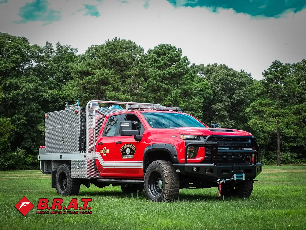 Exterior view of small fire truck showing cab, body compartments, and wheel/tire area.