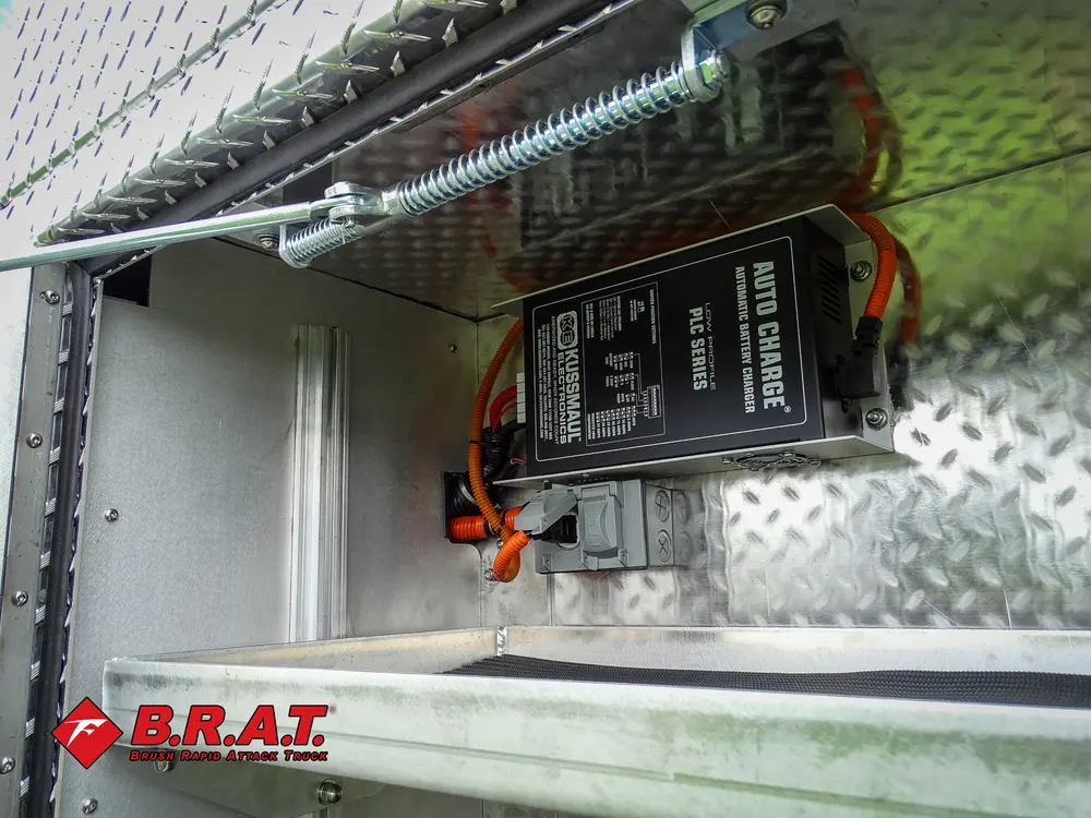 Exterior view of small fire truck showing cab, body compartments, and wheel/tire area.