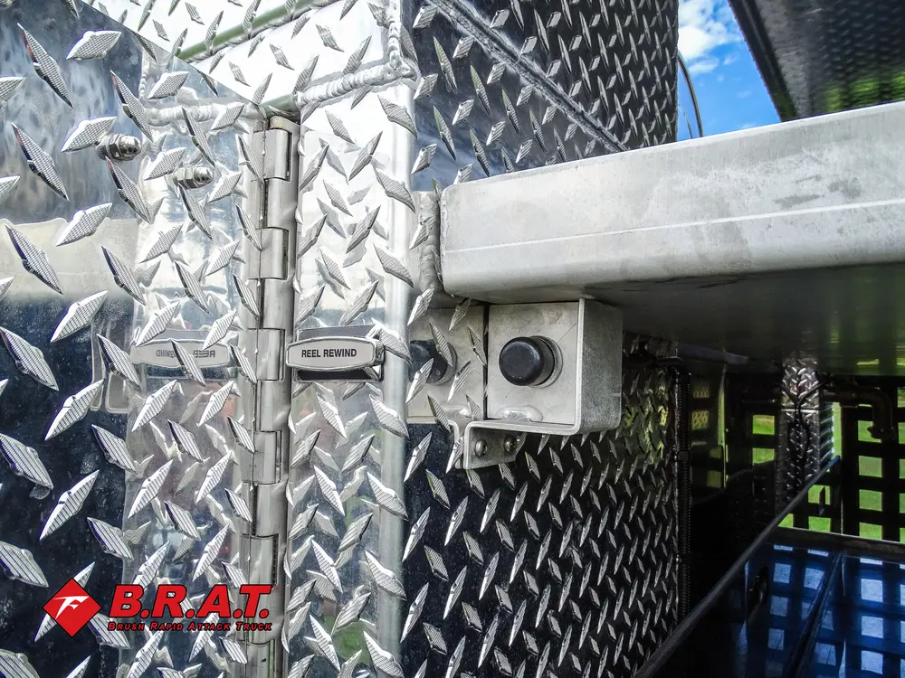 Exterior view of small fire truck showing cab, body compartments, and wheel/tire area.