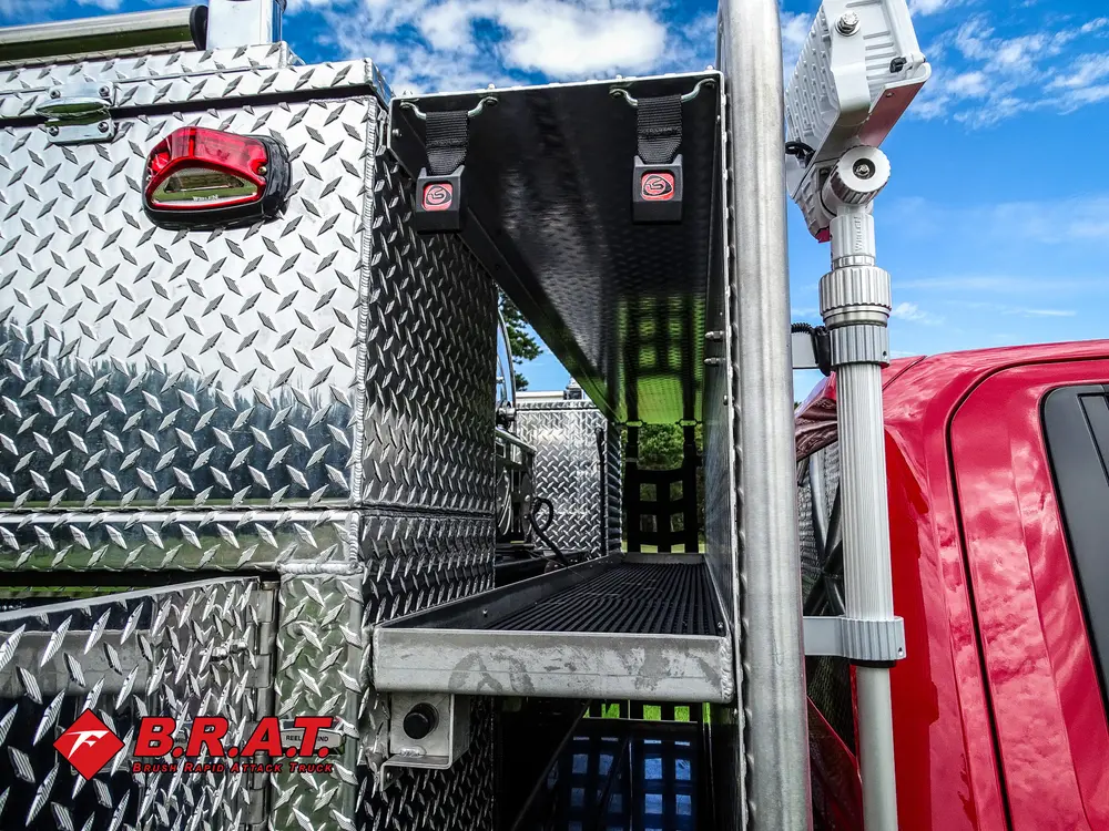 Exterior view of small fire truck showing cab, body compartments, and wheel/tire area.