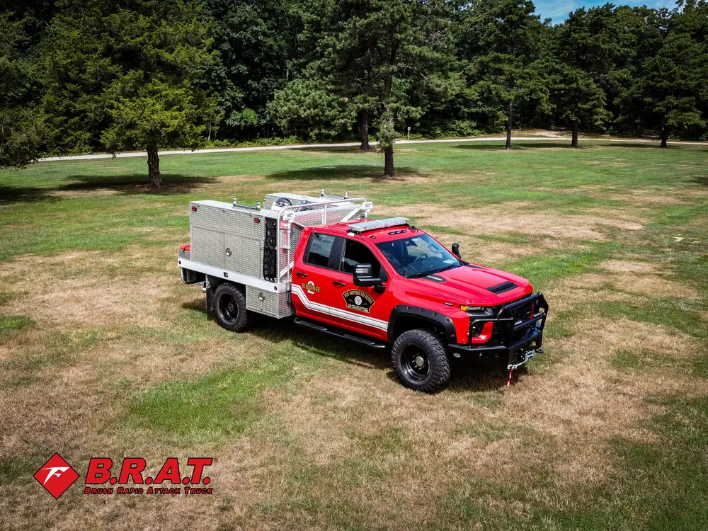 Exterior view of small fire truck showing cab, body compartments, and wheel/tire area.
