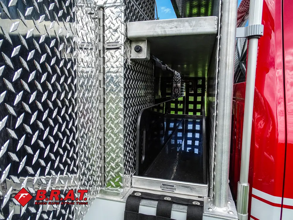 Exterior view of small fire truck showing cab, body compartments, and wheel/tire area.