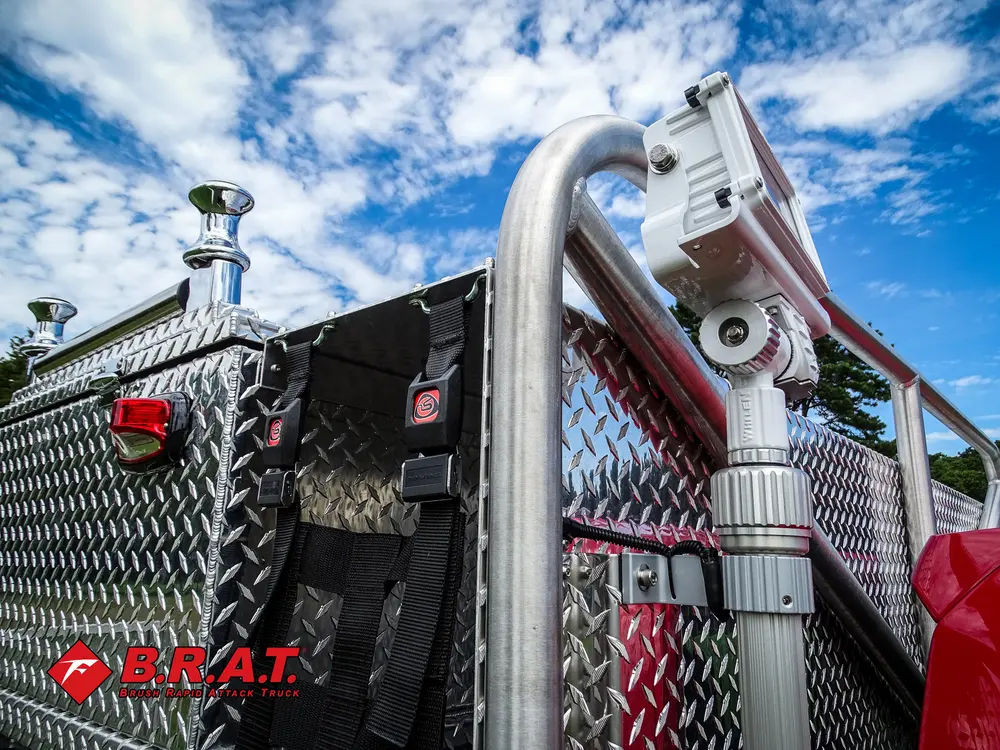 Exterior view of small fire truck showing cab, body compartments, and wheel/tire area.