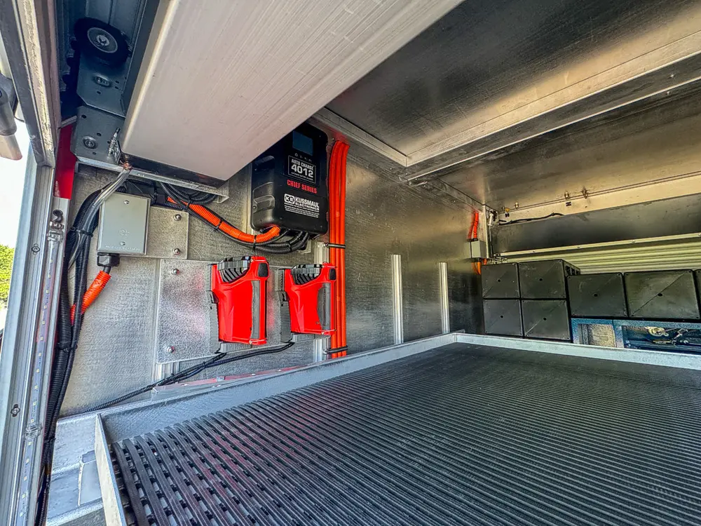 Compartment interior with mounted charger and orange wiring on side wall.