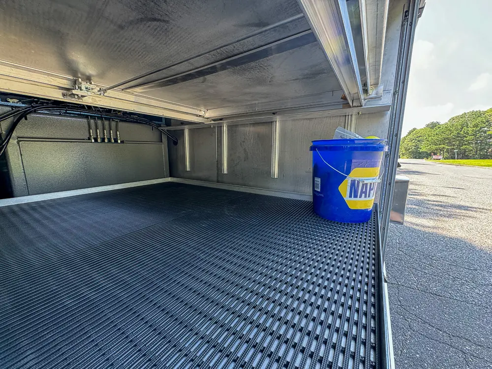 Long compartment interior with empty floor and small blue bucket.