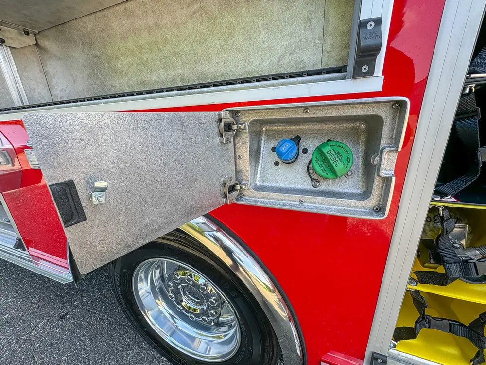 Open lower side access hatch with green connector fitting.