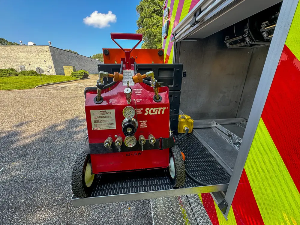 Portable red compressor/generator unit parked beside open compartment.