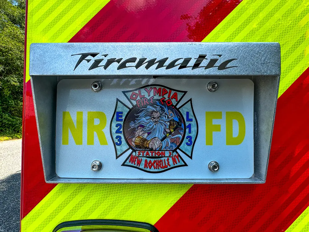 Firematic plate and New Rochelle Fire Dept emblem close-up.