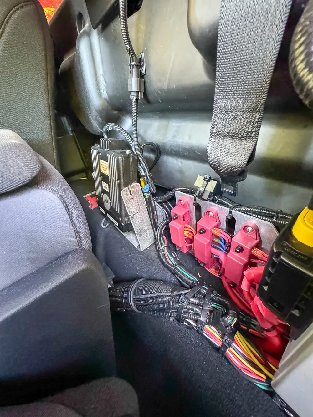 Rear seat area close-up with mounted red equipment packs and wiring.