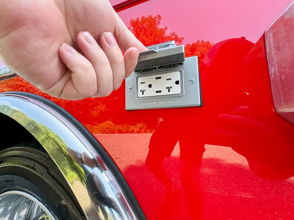 Exterior AC-style outlet close-up on side body panel.