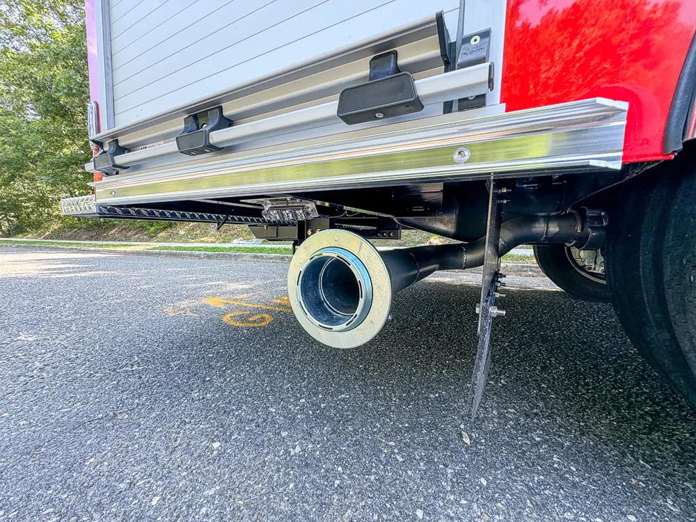 Underbody side view showing exhaust tip and lower support leg.