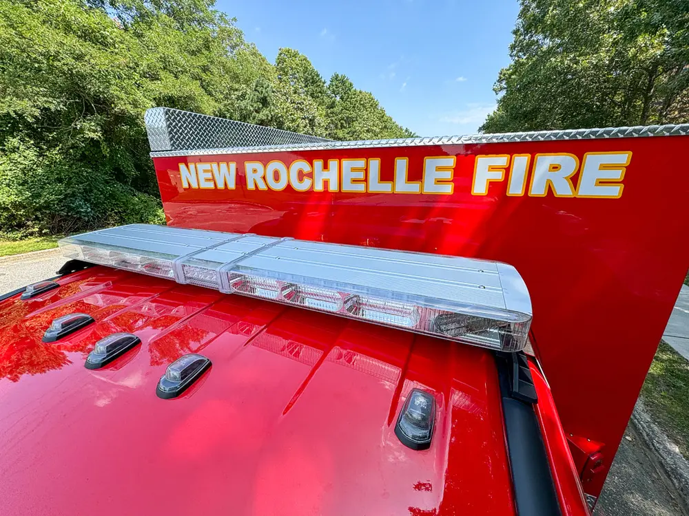 Roof lightbar and marker lights close-up beneath New Rochelle Fire signage.