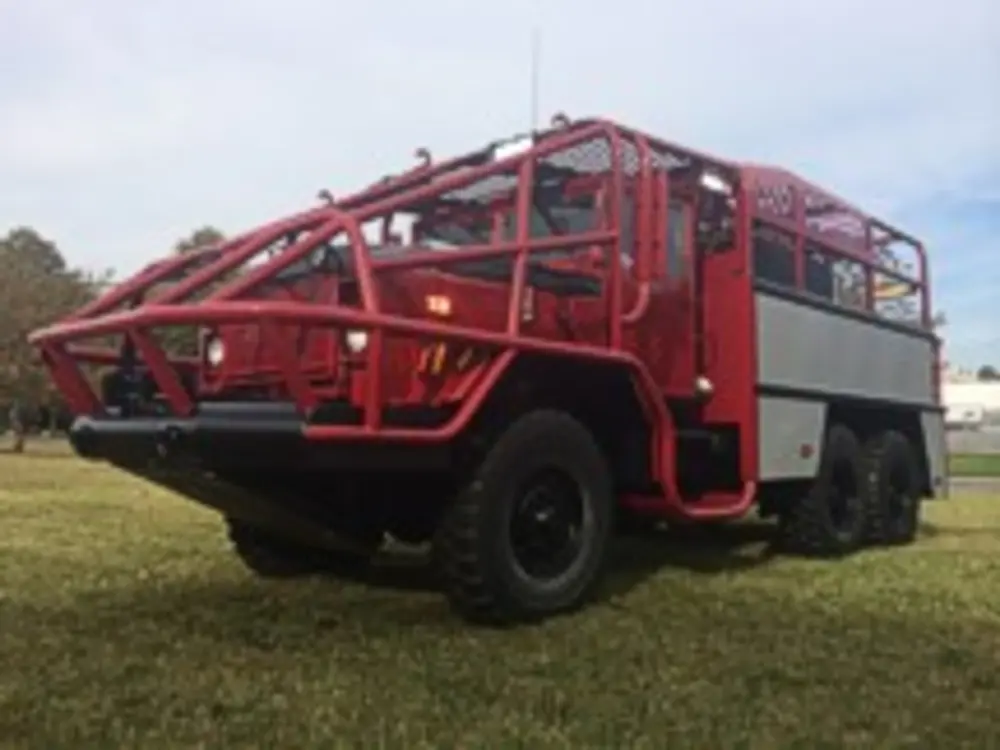 Exterior view of small fire truck showing cab, body compartments, and wheel/tire area.