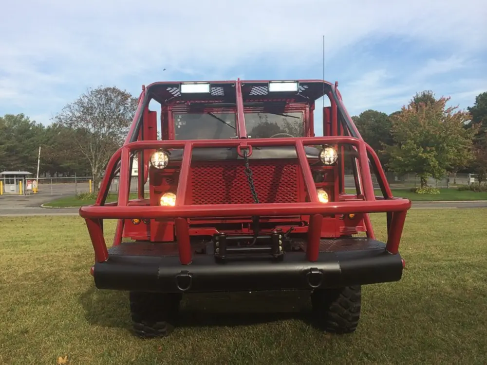 Exterior view of small fire truck showing cab, body compartments, and wheel/tire area.